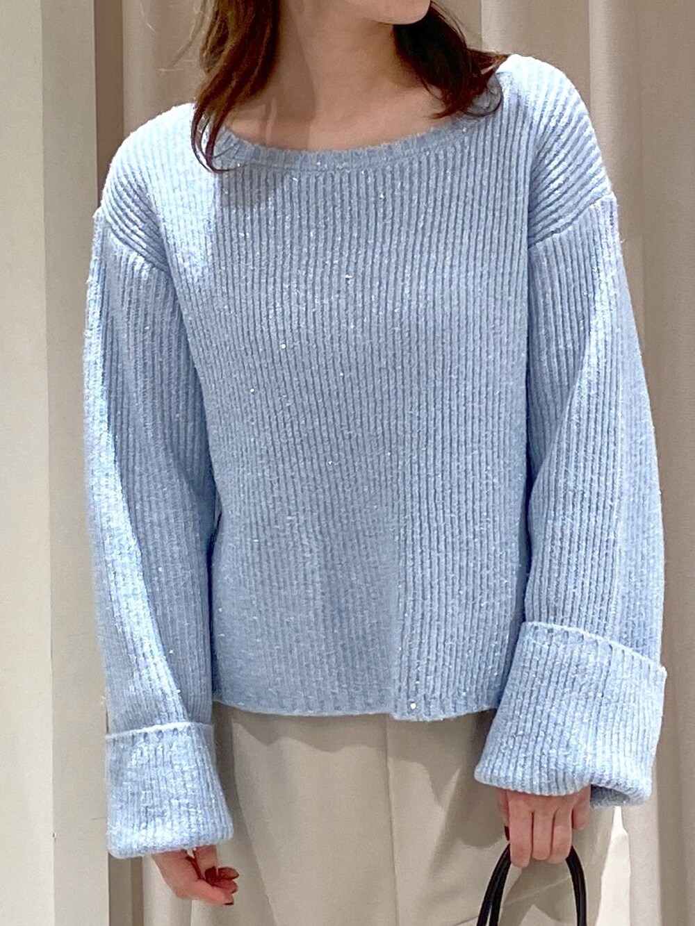 ブルー系のニット/セーター、ベージュ系のスカート、ブラック系のショルダーバッグを着用したレディースの冬コーディネートの3枚目の写真