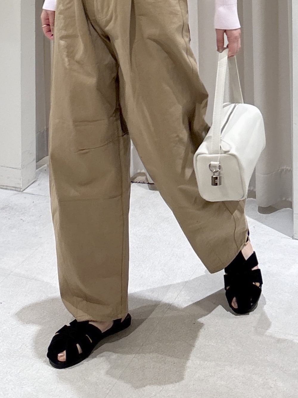 ピンク系のニット/セーター、ベージュ系のその他パンツ、ホワイト系のハンドバッグを着用したレディースの春コーディネートの2枚目の写真