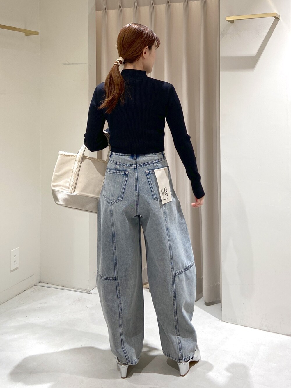 ブラック系のニット/セーター、シルバー系のトートバッグ、ブルー系のデニムパンツを着用したレディースの冬コーディネートの3枚目の写真