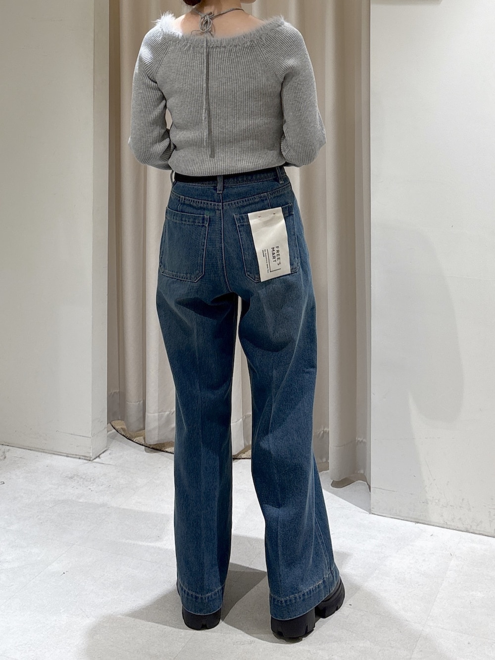 グレー系のニット/セーター、ブルー系のデニムパンツ、ホワイト系のトートバッグを着用したレディースの秋コーディネートの3枚目の写真