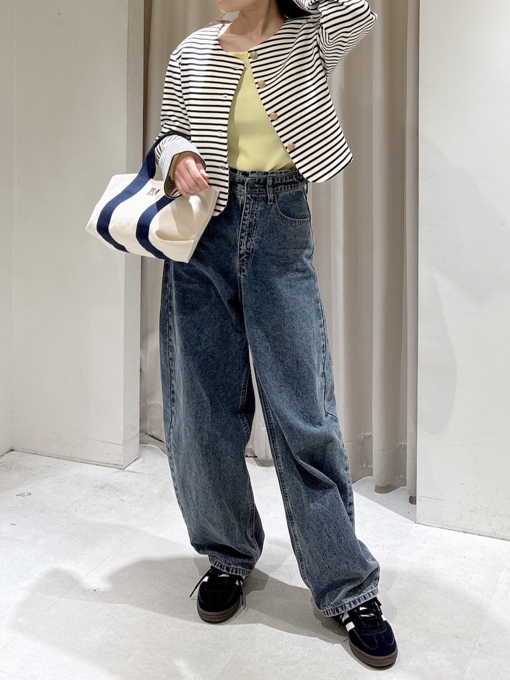 ブラック系のノーカラージャケット、イエロー系のニット/セーター、ブルー系のデニムパンツを着用したレディースの冬コーディネートの3枚目の写真