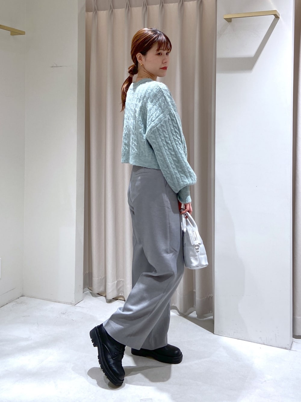 グリーン系のカーディガン/ボレロ、シルバー系のショルダーバッグ、グレー系のスラックスを着用したレディースの秋コーディネートの2枚目の写真