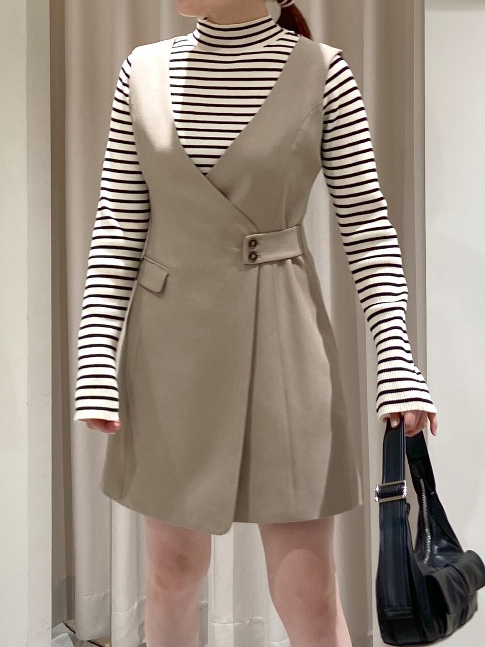 ベージュ系のワンピース、ホワイト系のニット/セーター、ブラック系のショルダーバッグを着用したレディースの冬コーディネートの2枚目の写真