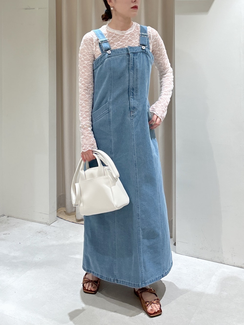 ブルー系のジャンパースカート、ホワイト系のTシャツ/カットソー、ブラウン系のサンダルを着用したレディースの春コーディネートの2枚目の写真