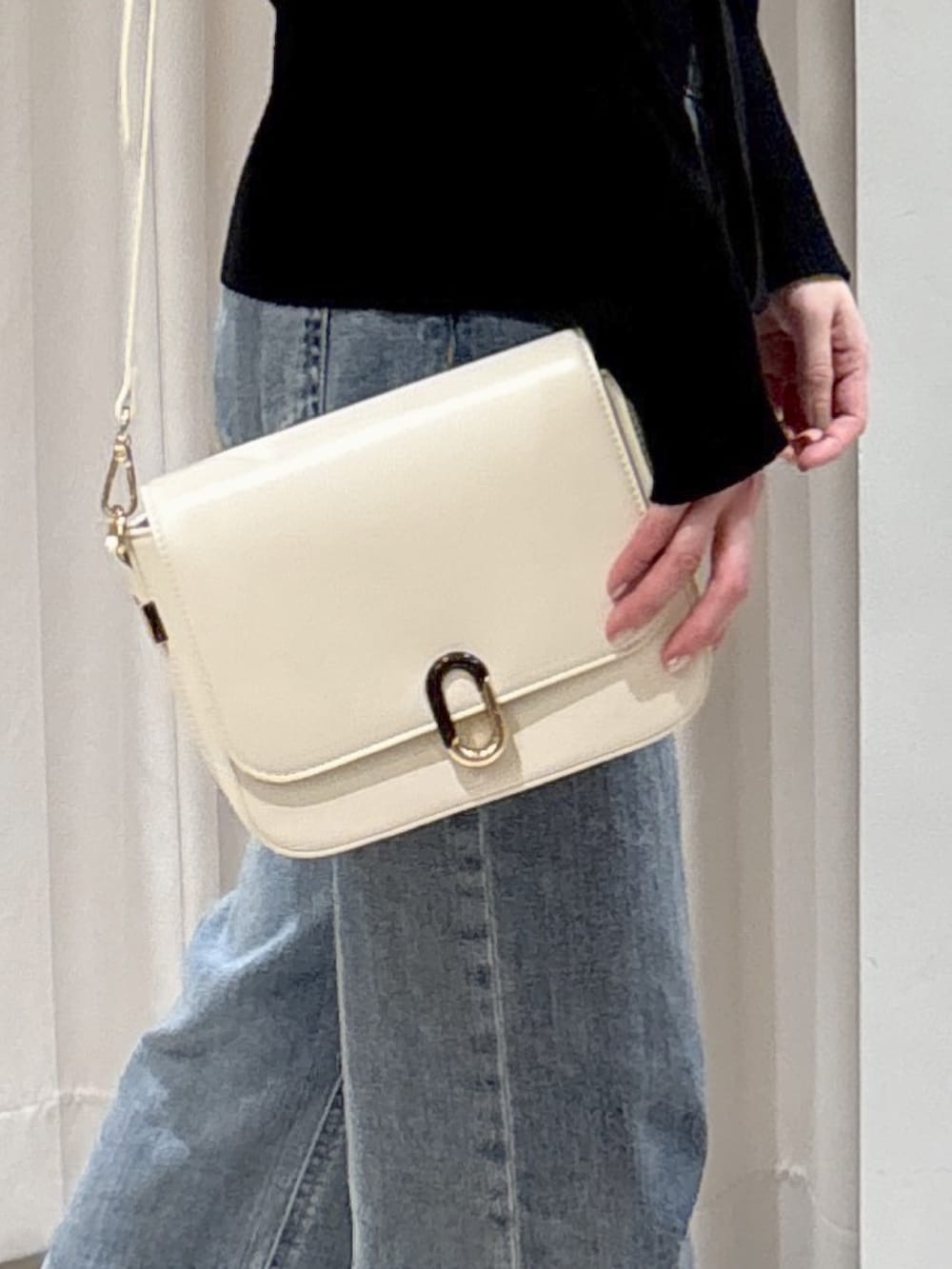 ブラック系のニット/セーター、ホワイト系のハンドバッグ、ブルー系のデニムパンツを着用したレディースの冬コーディネートの6枚目の写真