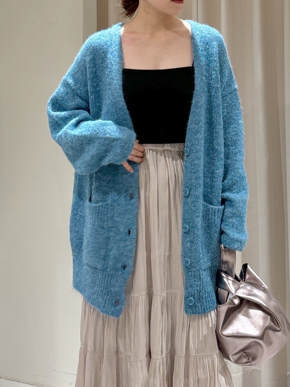 ブルー系のカーディガン/ボレロ、ブラック系のキャミソール、ホワイト系のスカートを着用したレディースの秋コーディネートの5枚目の写真