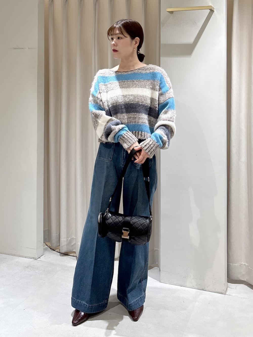 グレー系のニット/セーター、ブラック系のショルダーバッグ、ブルー系のデニムパンツを着用したレディースの秋コーディネートの6枚目の写真