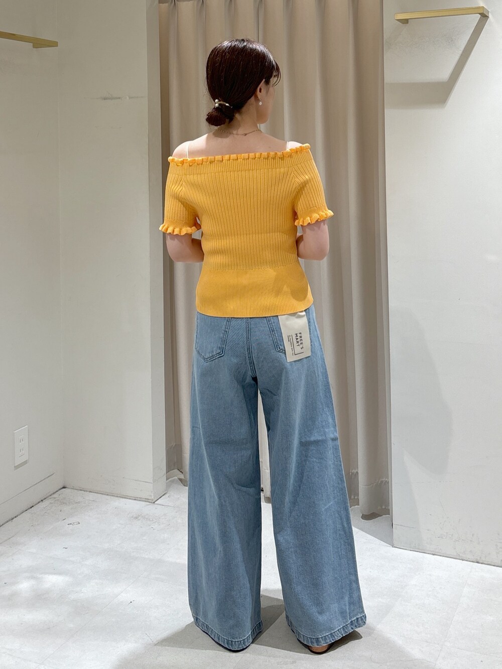 オレンジ系のニット/セーター、ブラック系のハンドバッグ、ブルー系のデニムパンツを着用したレディースの夏コーディネートの3枚目の写真