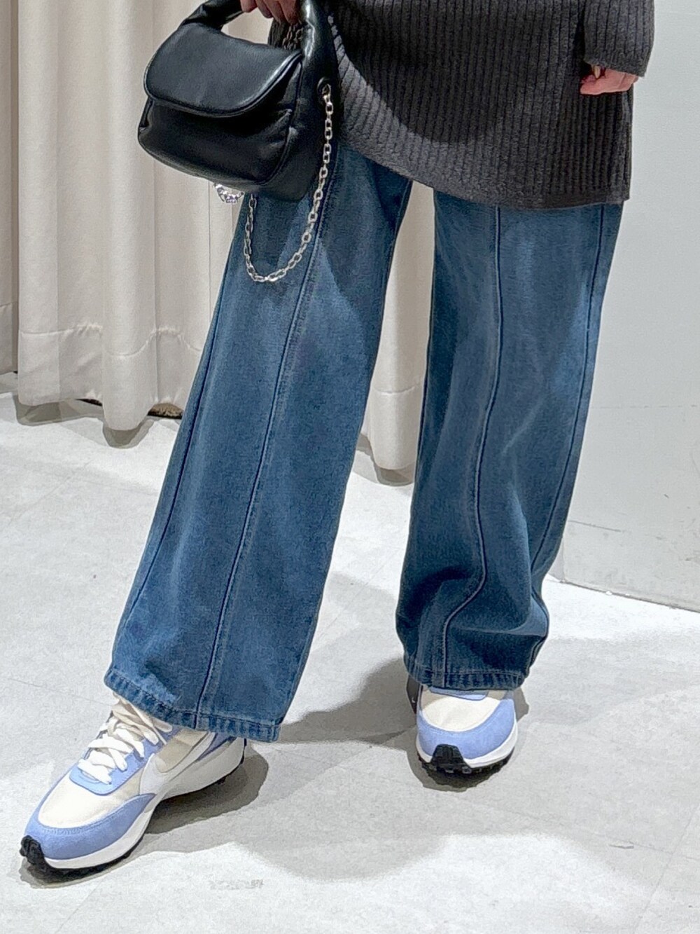 グレー系のワンピース、ブラック系のショルダーバッグ、ブルー系のデニムパンツを着用したレディースの冬コーディネートの5枚目の写真