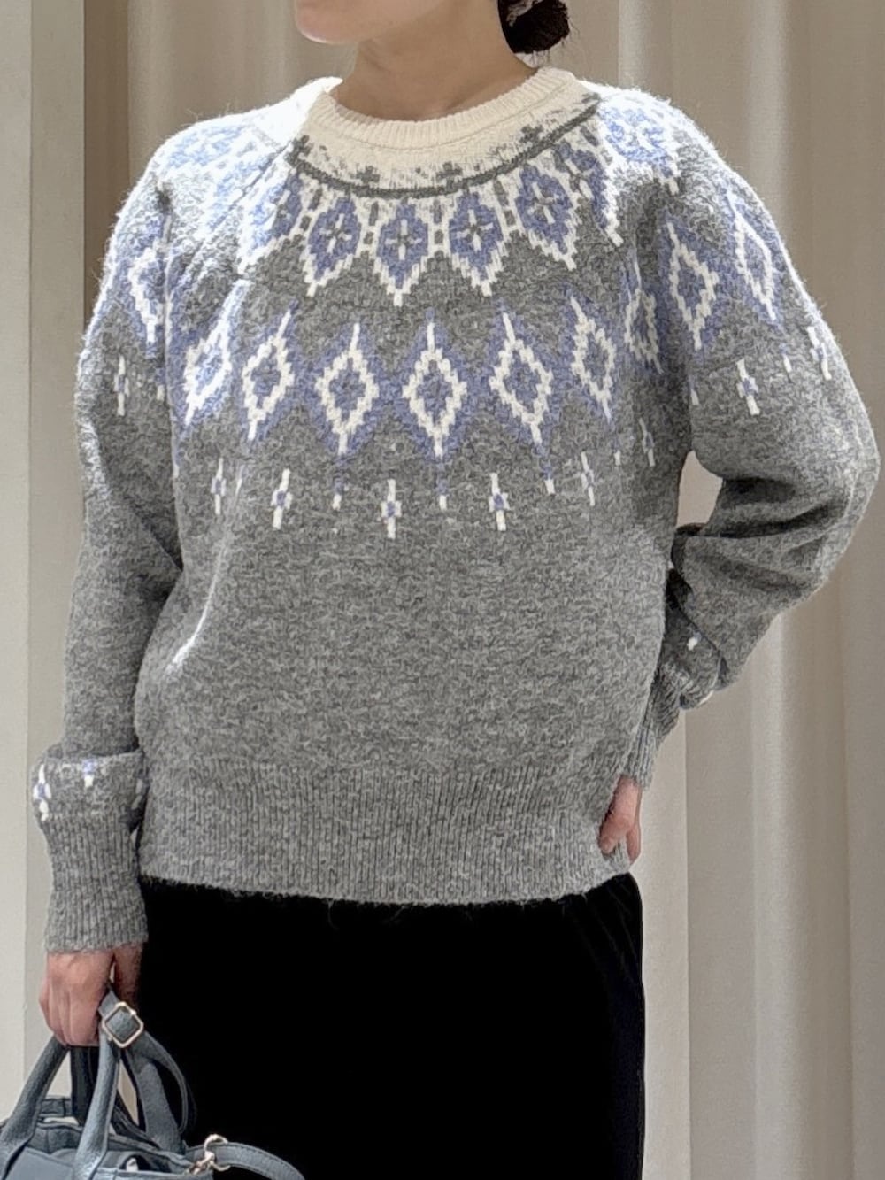 グレー系のニット/セーター、ブラック系のスカート、ブルー系のハンドバッグを着用したレディースの冬コーディネートの3枚目の写真