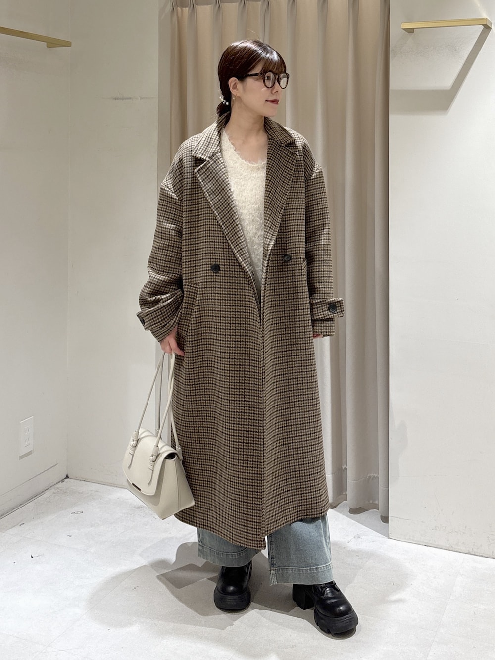 ベージュ系のチェスターコート、ホワイト系のニット/セーター、ホワイト系のショルダーバッグを着用したレディースの冬コーディネートの3枚目の写真