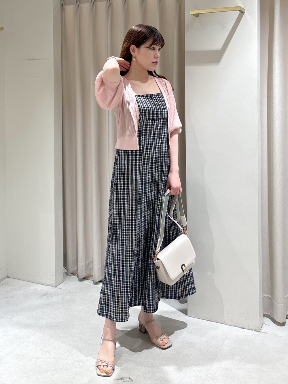 ブラック系のワンピース、ピンク系のカーディガン/ボレロ、ホワイト系のショルダーバッグを着用したレディースの春コーディネートの2枚目の写真