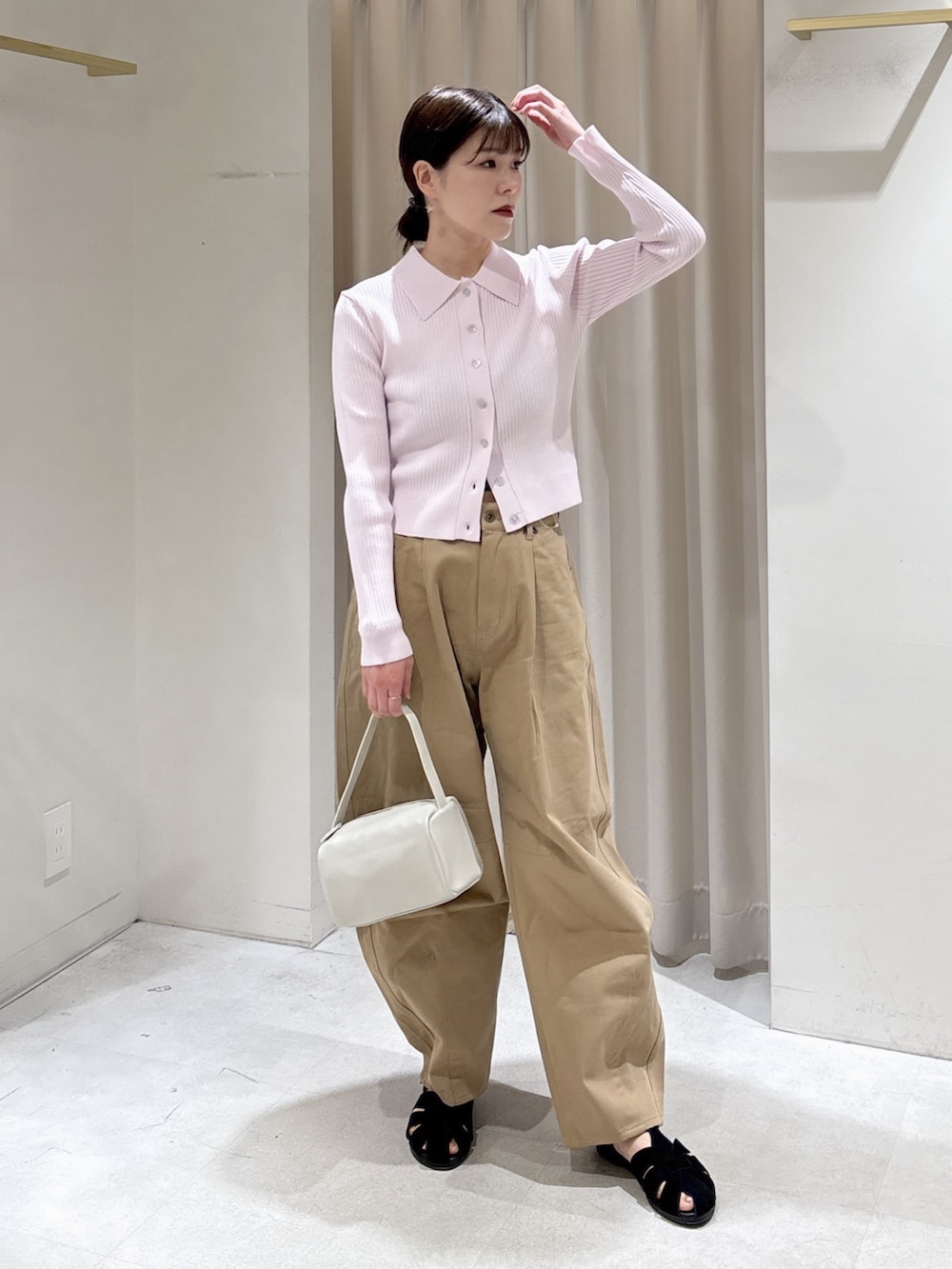 ピンク系のニット/セーター、ベージュ系のその他パンツ、ホワイト系のハンドバッグを着用したレディースの春コーディネートの4枚目の写真