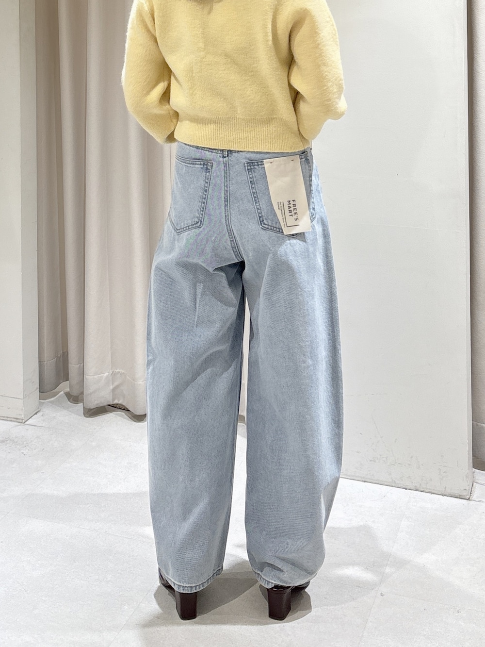 イエロー系のニット/セーター、ブラウン系のパンプス、ブルー系のデニムパンツを着用したレディースの冬コーディネートの5枚目の写真