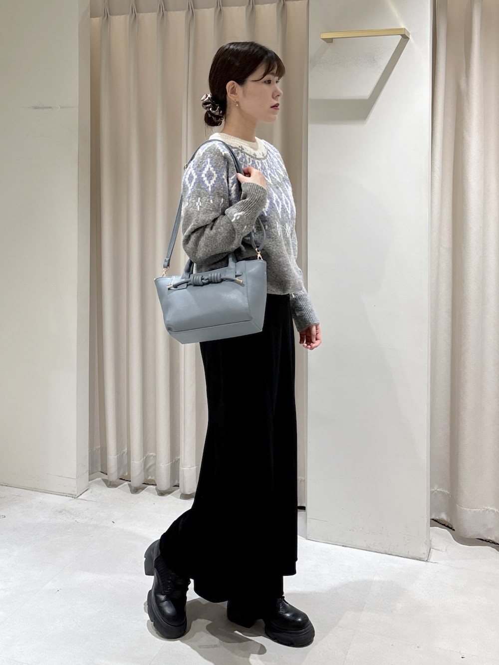 グレー系のニット/セーター、ブラック系のスカート、ブルー系のハンドバッグを着用したレディースの冬コーディネートの2枚目の写真