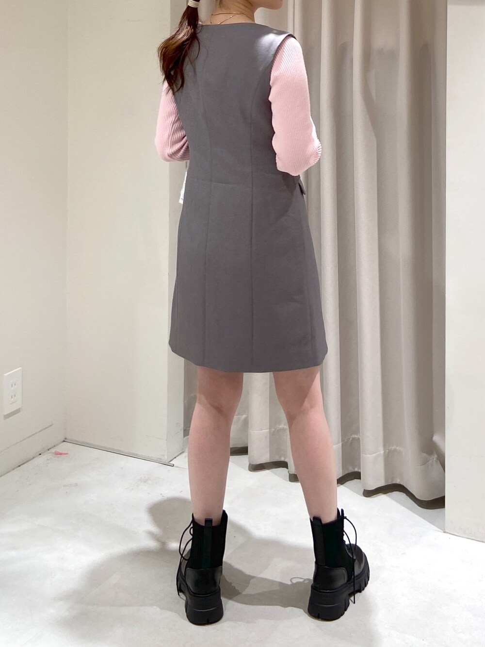 グレー系のワンピース、シルバー系のショルダーバッグ、ブラック系のブーツを着用したレディースの春コーディネートの2枚目の写真