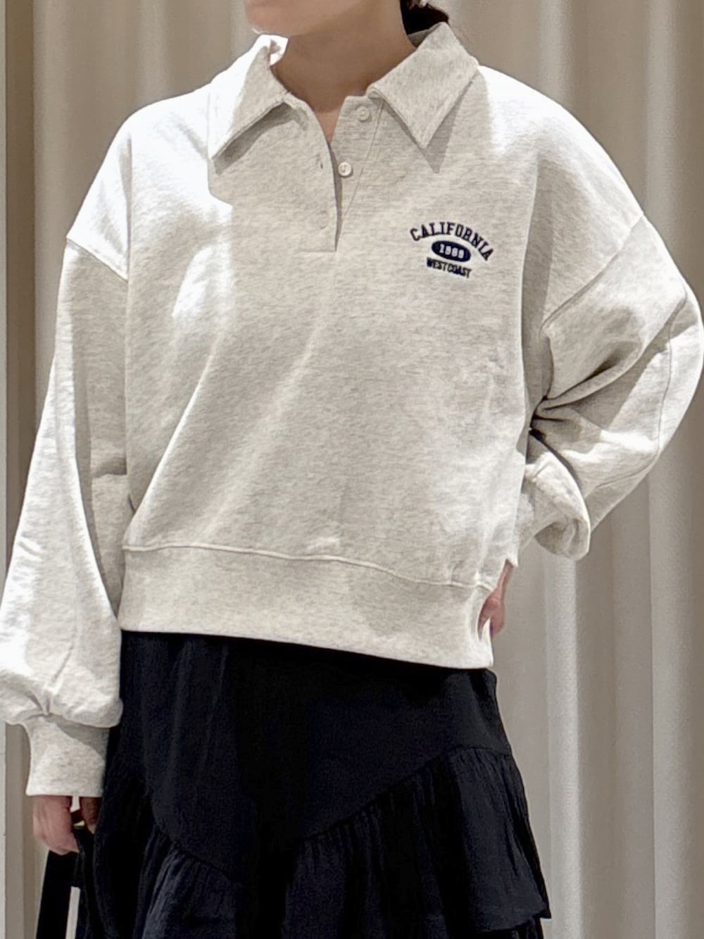 ホワイト系のスウェット、ブラック系のスカート、ブラック系のショルダーバッグを着用したレディースの秋コーディネートの3枚目の写真