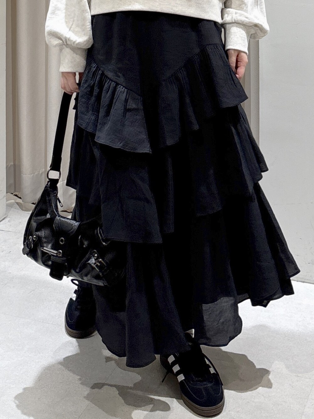 ホワイト系のスウェット、ブラック系のスカート、ブラック系のショルダーバッグを着用したレディースの秋コーディネートの4枚目の写真