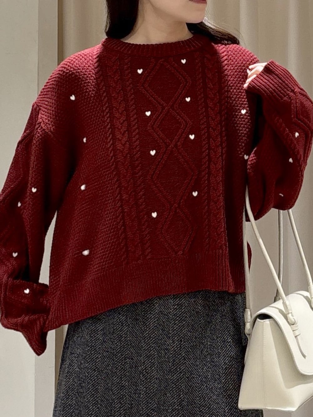 レッド系のニット/セーター、ホワイト系のショルダーバッグ、ブラック系のスカートを着用したレディースの冬コーディネートの3枚目の写真