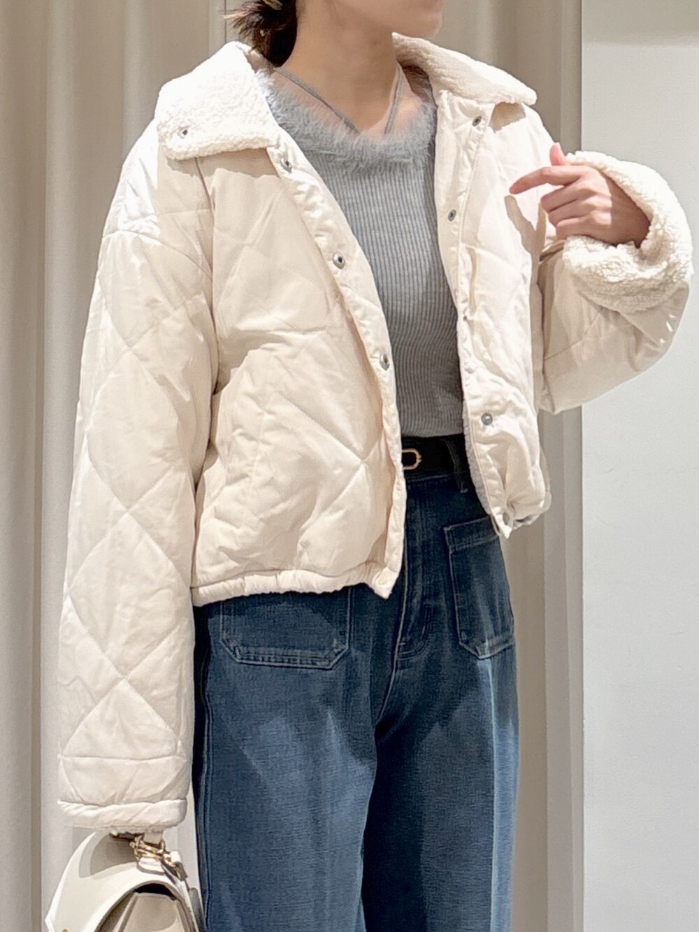 グレー系のニット/セーター、ブルー系のデニムパンツ、ホワイト系のトートバッグを着用したレディースの秋コーディネートの6枚目の写真