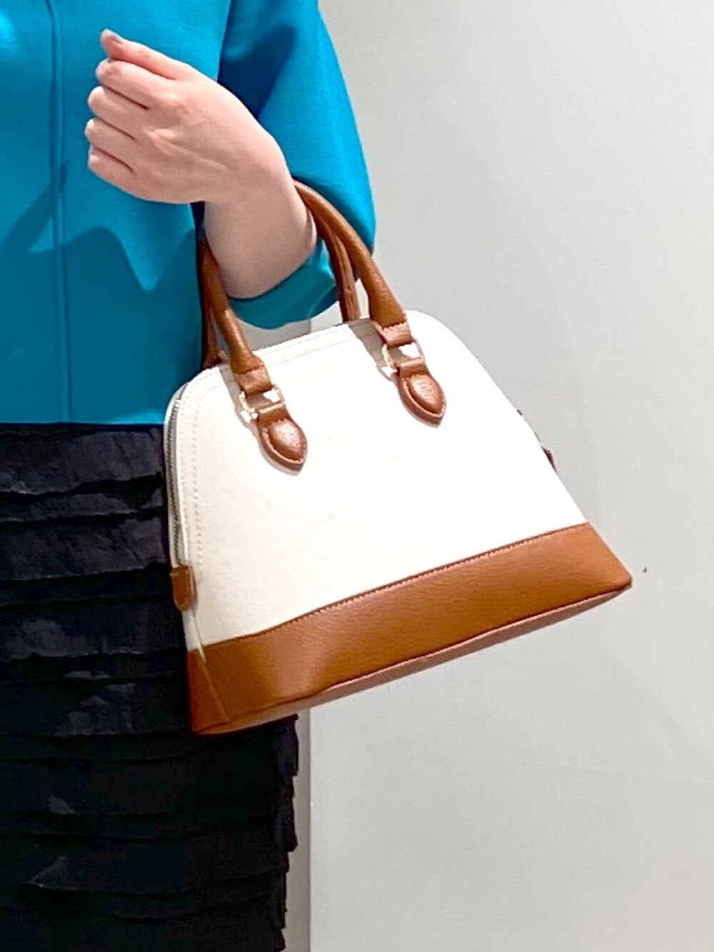 ブラック系のスカート、ブルー系のニット/セーター、ブラウン系のショルダーバッグを着用したレディースの春コーディネートの5枚目の写真