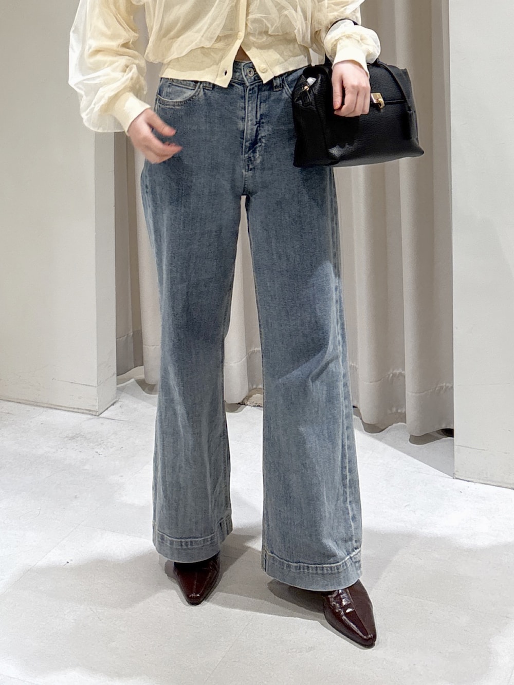 イエロー系のニット/セーター、ブルー系のデニムパンツ、ブラック系のショルダーバッグを着用したレディースの冬コーディネートの2枚目の写真