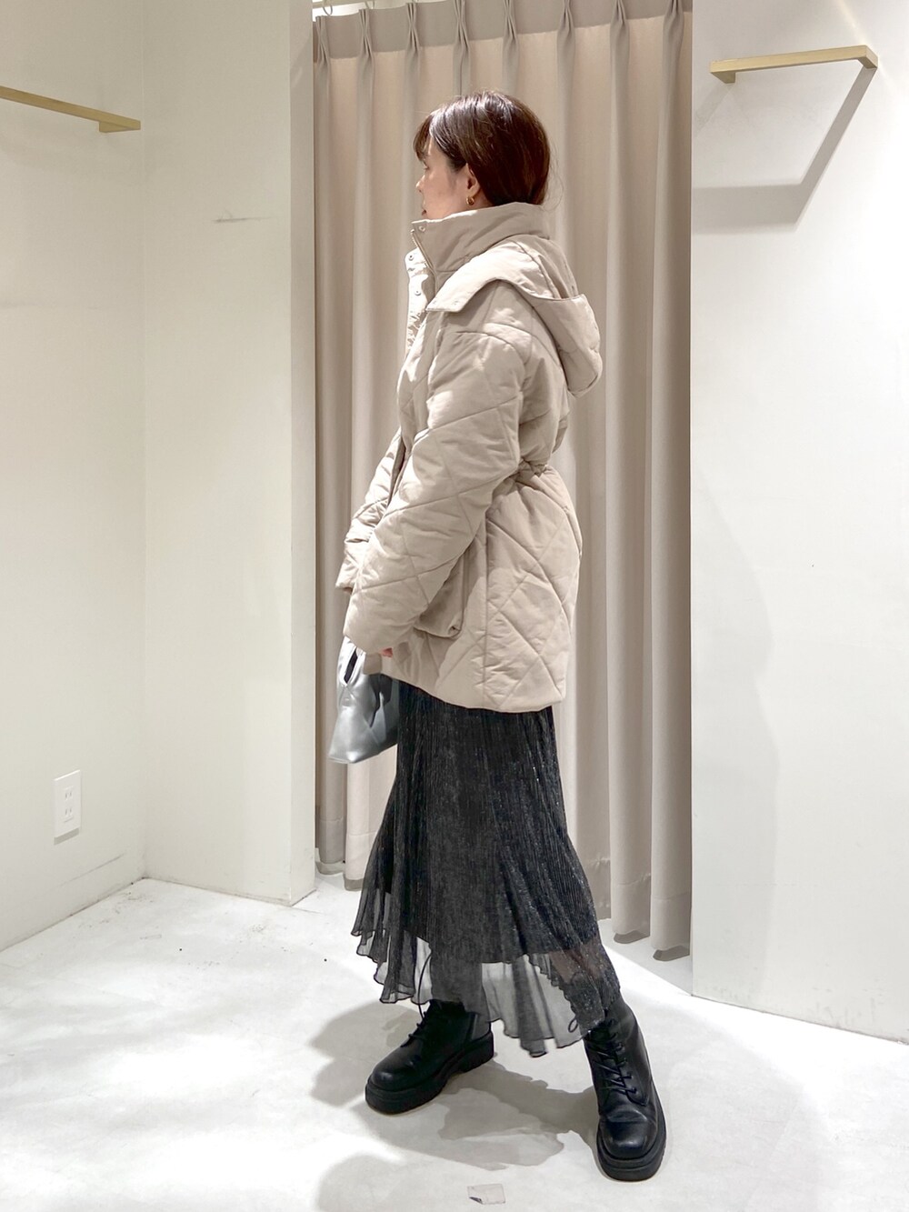 ベージュ系のダウンジャケット/コート、ブラック系のスカート、シルバー系のショルダーバッグを着用したレディースの秋コーディネートの2枚目の写真