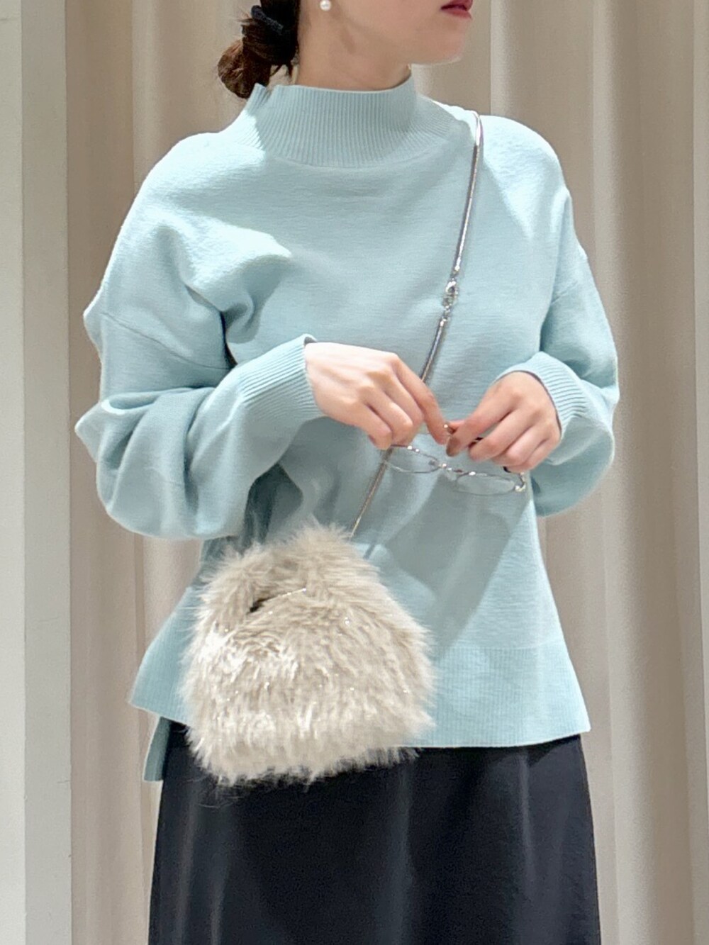 ブルー系のニット/セーター、ベージュ系のショルダーバッグ、グレー系のスカートを着用したレディースの冬コーディネートの5枚目の写真