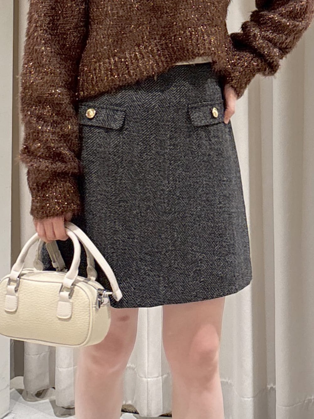 ブラウン系のニット/セーター、ブラック系のスカート、ブラック系のブーツを着用したレディースの冬コーディネートの4枚目の写真