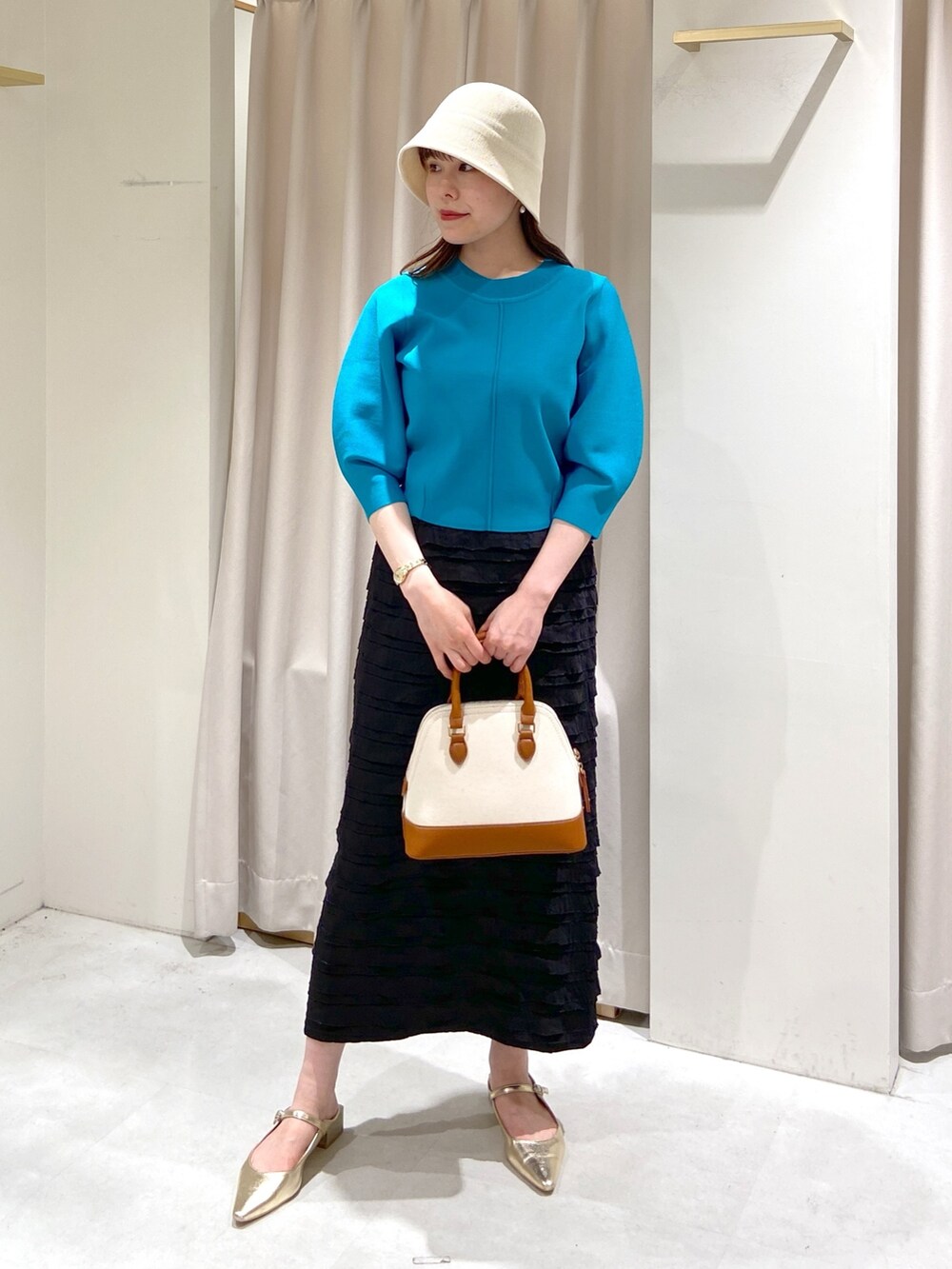 ブラック系のスカート、ブルー系のニット/セーター、ブラウン系のショルダーバッグを着用したレディースの春コーディネートの8枚目の写真