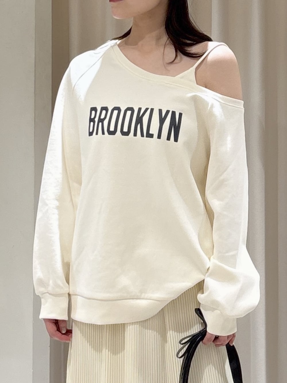 ホワイト系のスウェット、ホワイト系のスカート、ブラック系のショルダーバッグを着用したレディースの春コーディネートの3枚目の写真