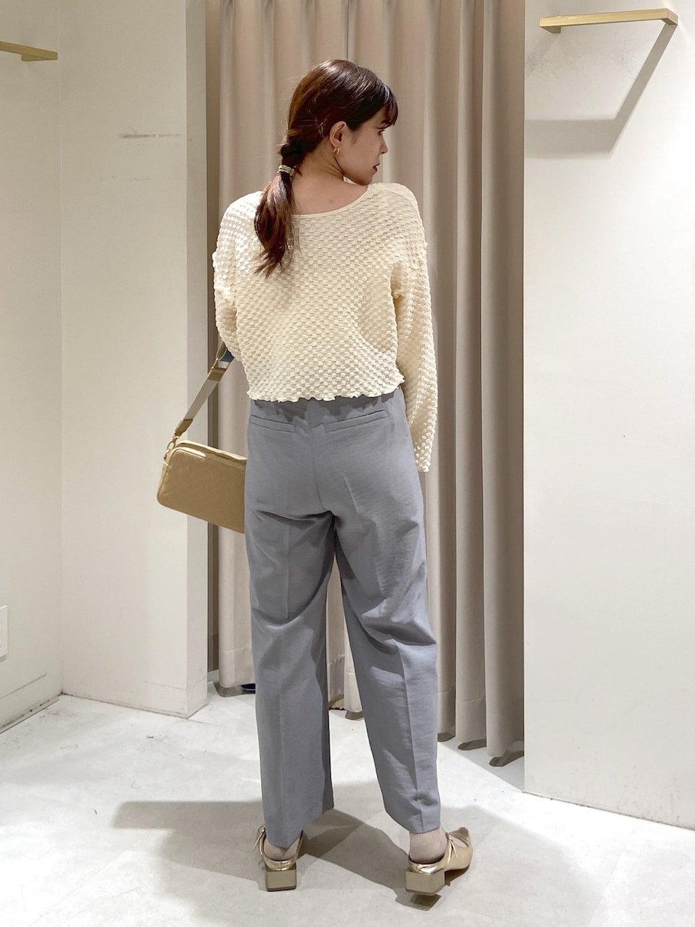 ホワイト系のカーディガン/ボレロ、ホワイト系のキャミソール、グレー系のスラックスを着用したレディースの春コーディネートの2枚目の写真