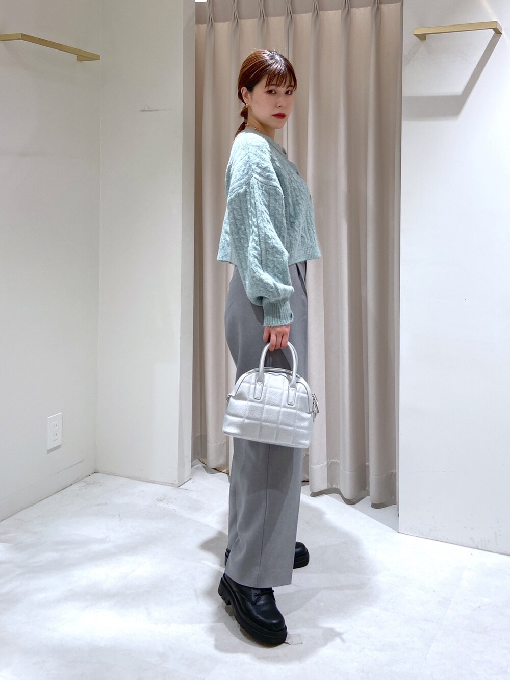 グリーン系のカーディガン/ボレロ、シルバー系のショルダーバッグ、グレー系のスラックスを着用したレディースの秋コーディネートの3枚目の写真