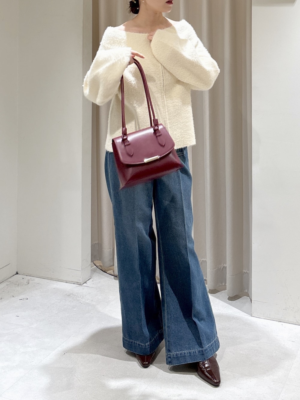 ホワイト系のニット/セーター、レッド系のトートバッグ、ブルー系のデニムパンツを着用したレディースの秋コーディネートの6枚目の写真