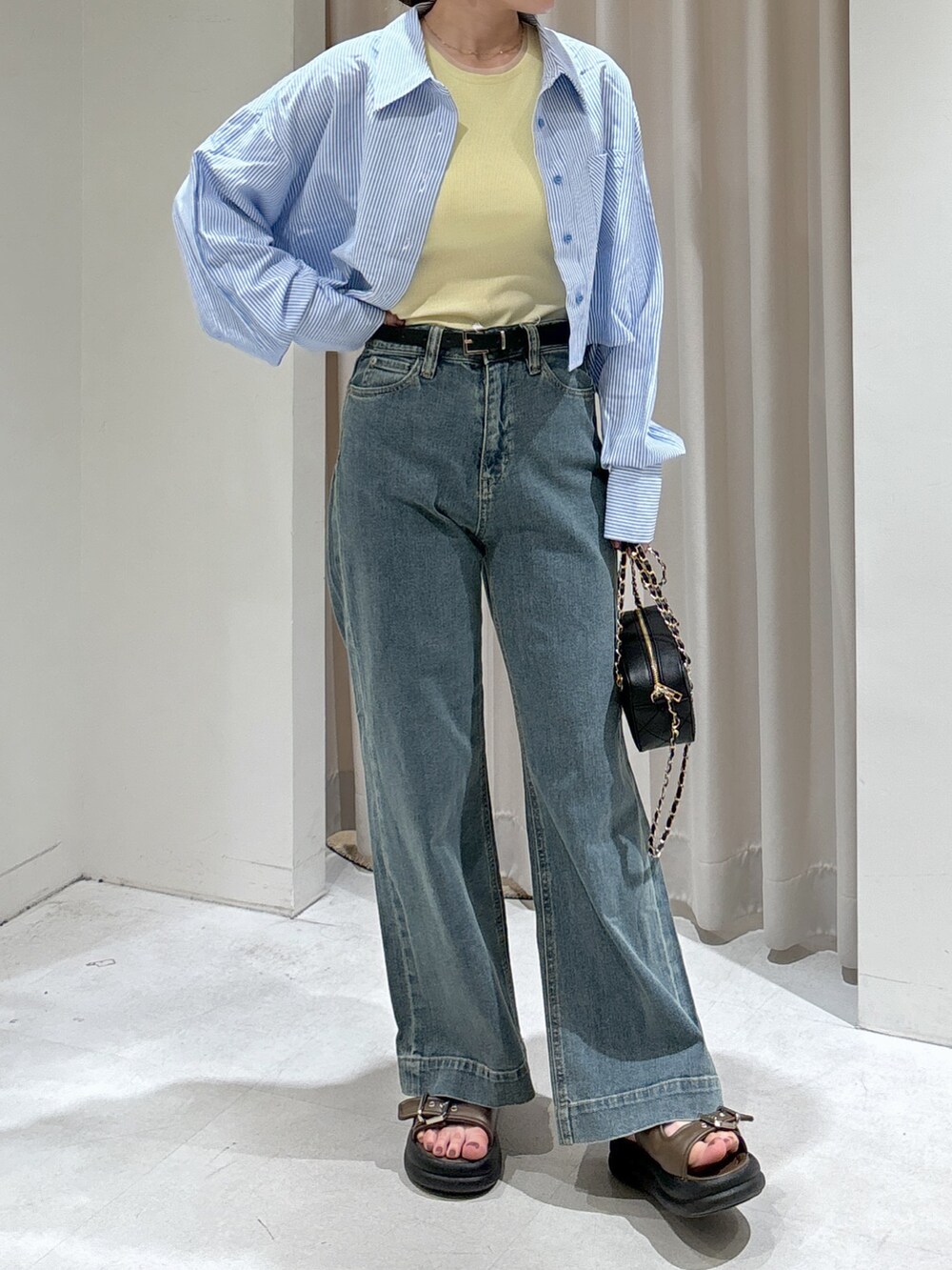 ブルー系のシャツ/ブラウス、イエロー系のタンクトップ、ブラック系のショルダーバッグを着用したレディースの夏コーディネートの3枚目の写真