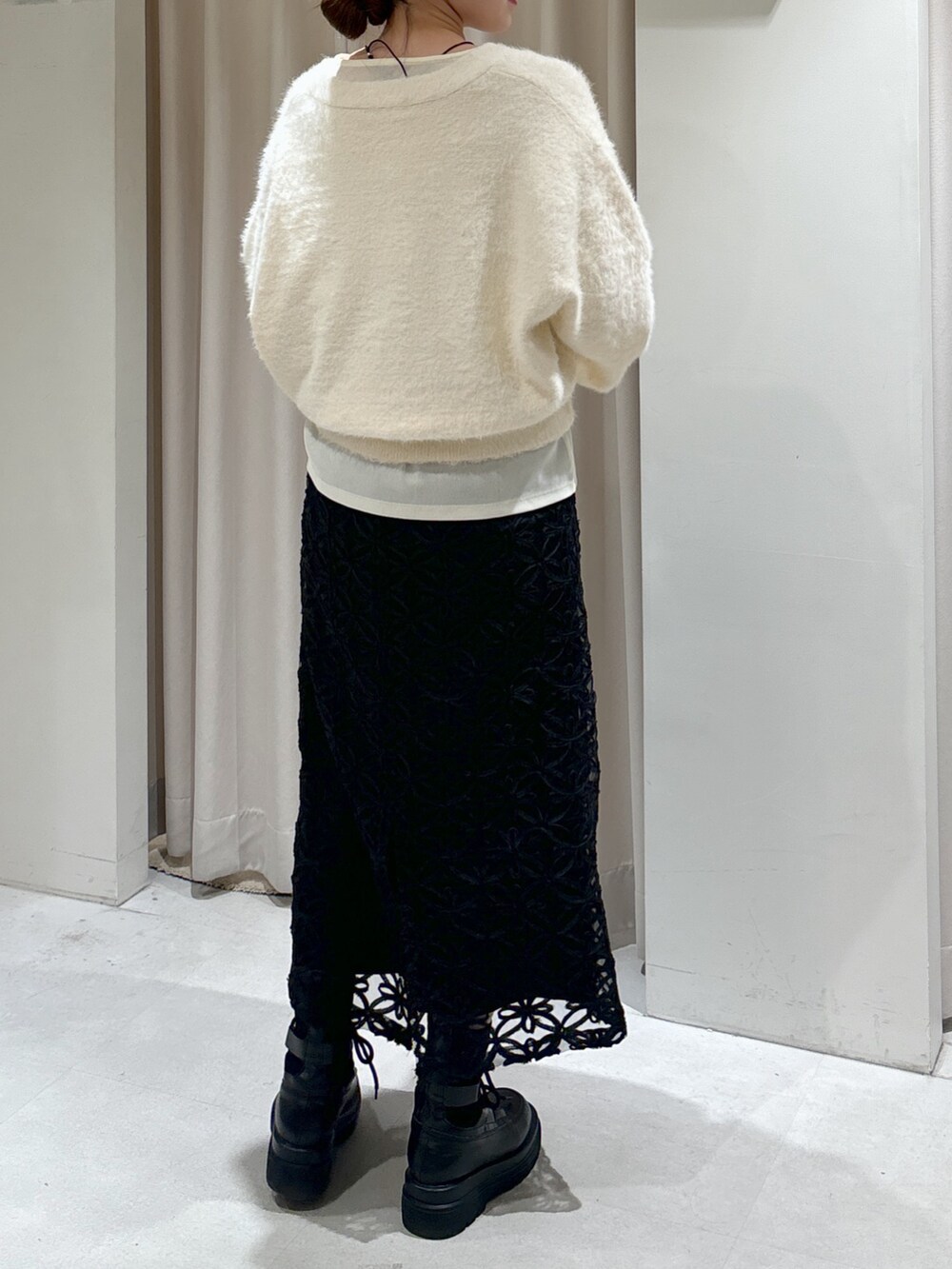 ブラック系のスカート、ベージュ系のショルダーバッグ、ブラック系のブーツを着用したレディースの冬コーディネートの5枚目の写真