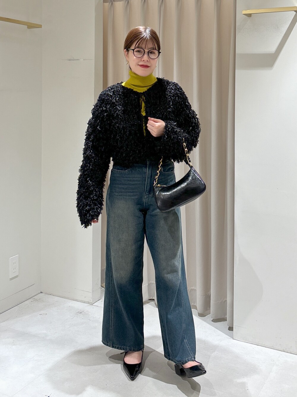 ブラック系のカーディガン/ボレロ、イエロー系のニット/セーター、ブルー系のデニムパンツを着用したレディースの秋コーディネートの8枚目の写真