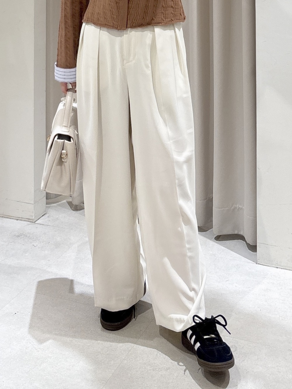 ホワイト系のトレンチコート、ベージュ系のニット/セーター、ブラック系のスニーカーを着用したレディースの冬コーディネートの9枚目の写真