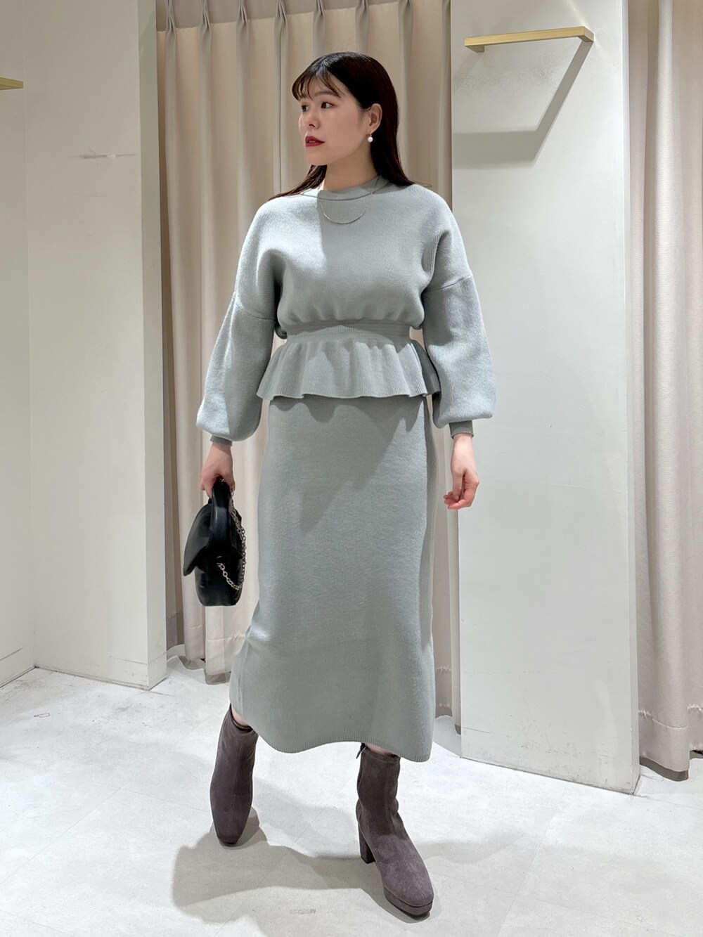 グリーン系のワンピース、ブラック系のショルダーバッグ、グレー系のブーツを着用したレディースの冬コーディネートの2枚目の写真