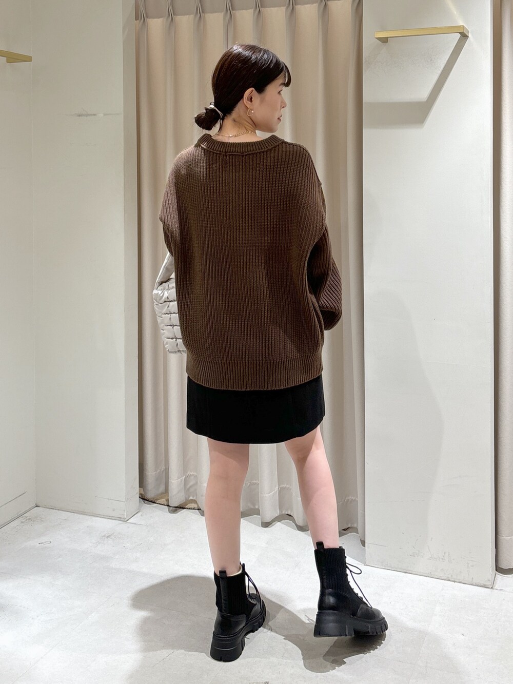 ブラウン系のニット/セーター、ホワイト系のハンドバッグ、ブラック系のスカートを着用したレディースの秋コーディネートの8枚目の写真