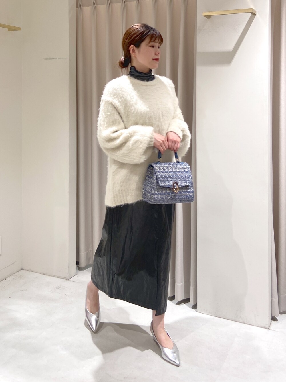 ホワイト系のニット/セーター、ブラック系のTシャツ/カットソー、ブルー系のショルダーバッグを着用したレディースの冬コーディネートの2枚目の写真