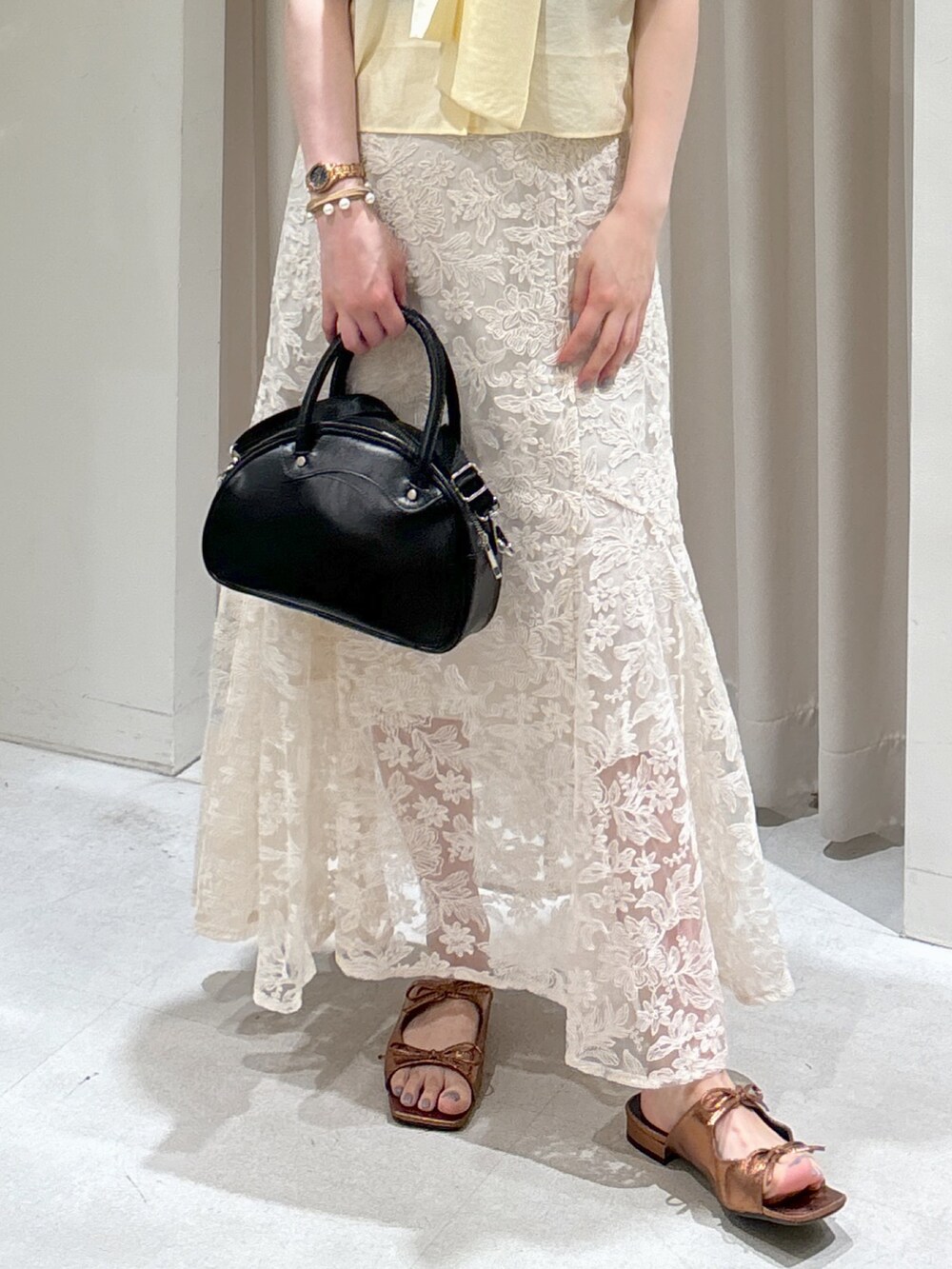 イエロー系のシャツ/ブラウス、ブラック系のトートバッグ、ホワイト系のスカートを着用したレディースの夏コーディネートの4枚目の写真