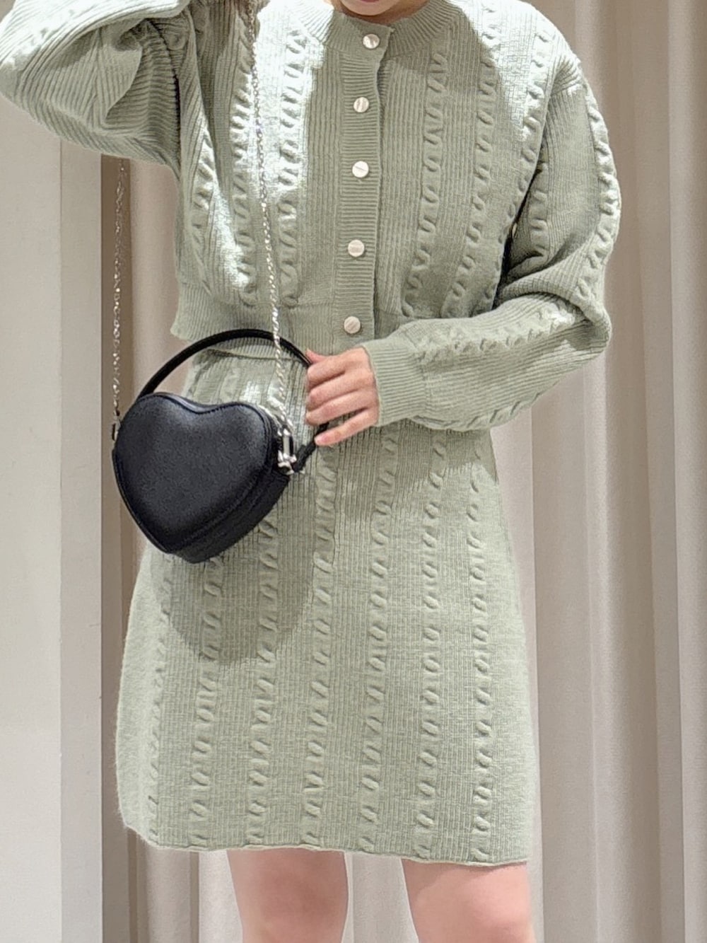 グリーン系のワンピース、ブラック系のブーツ、ブラック系のショルダーバッグを着用したレディースの冬コーディネートの3枚目の写真