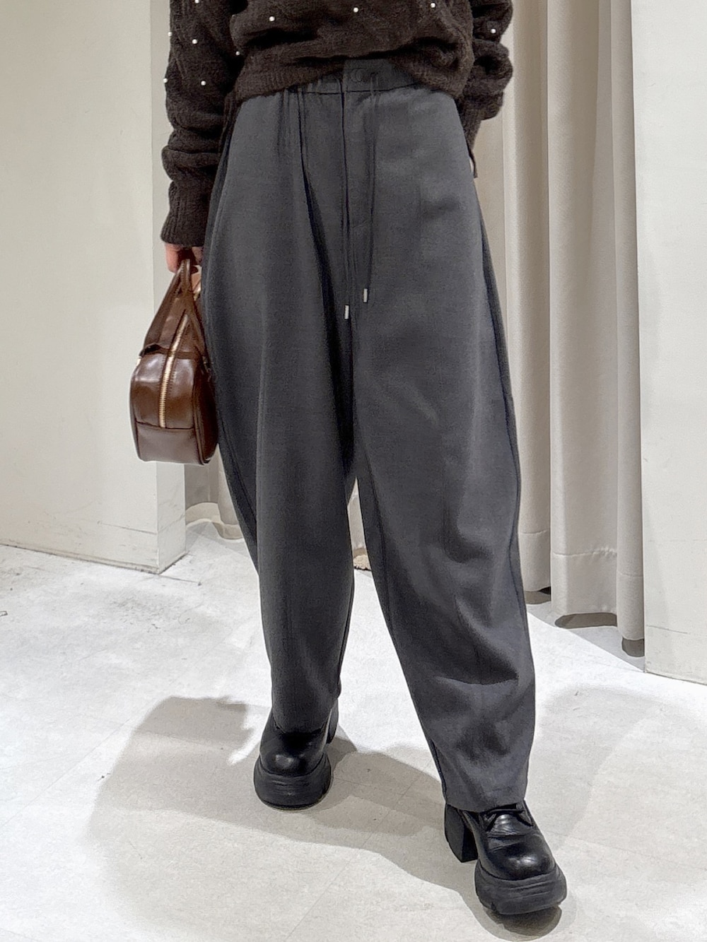 ブラウン系のニット/セーター、グレー系のその他パンツ、ブラウン系のハンドバッグを着用したレディースの冬コーディネートの3枚目の写真