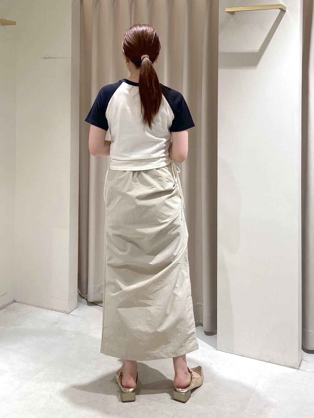 ベージュ系のスカート、グリーン系のハンドバッグ、ゴールド系のパンプスを着用したレディースの春コーディネートの4枚目の写真