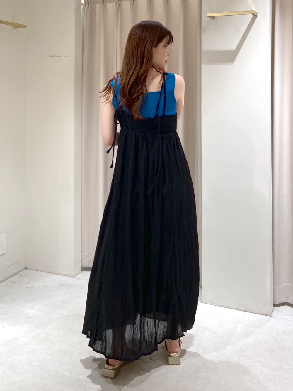 ブルー系のタンクトップ、ブラック系のハンドバッグ、ゴールド系のパンプスを着用したレディースの春コーディネートの4枚目の写真