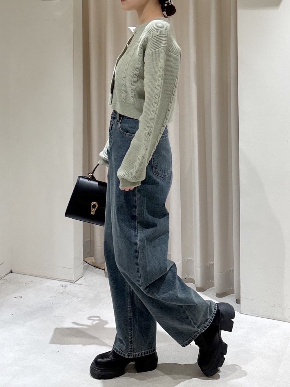 グリーン系のワンピース、ブルー系のデニムパンツ、ブラック系のトートバッグを着用したレディースの冬コーディネートの5枚目の写真