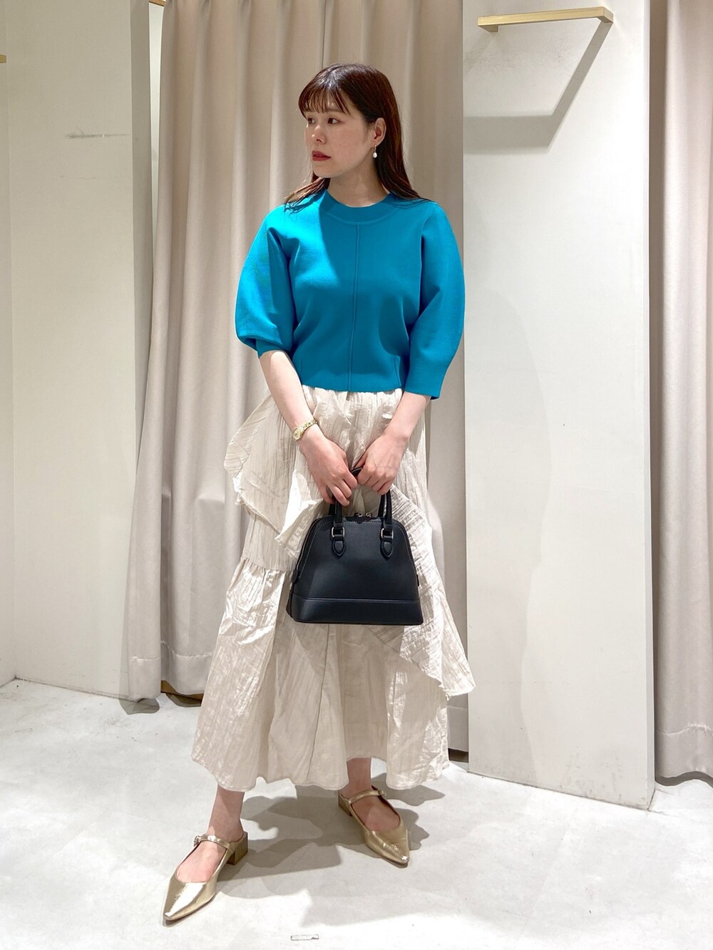 ブルー系のニット/セーター、ホワイト系のスカート、ブラック系のショルダーバッグを着用したレディースの冬コーディネートの4枚目の写真