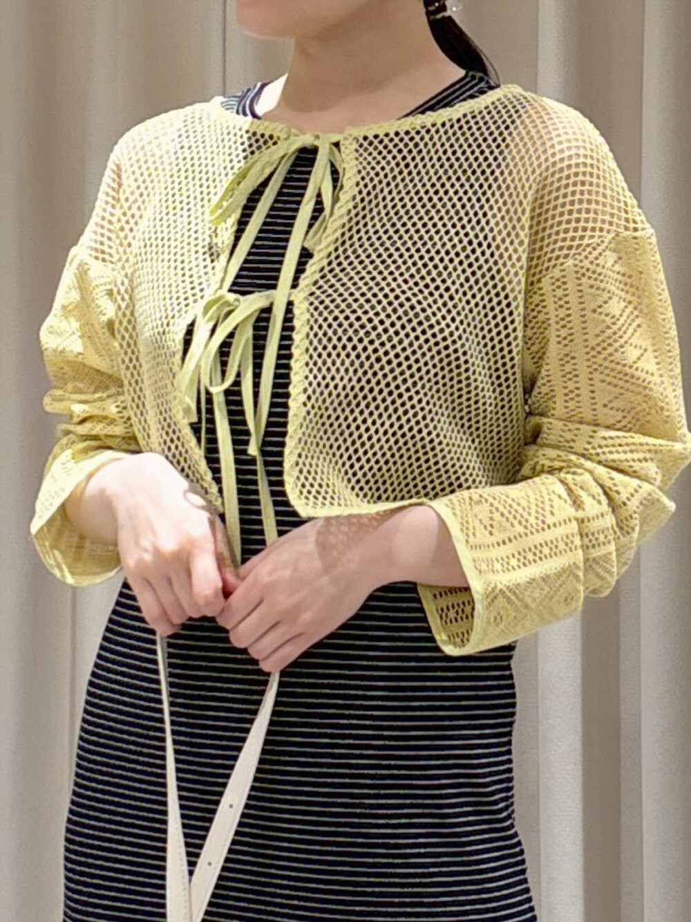 イエロー系のカーディガン/ボレロ、ブラック系のワンピース、ホワイト系のショルダーバッグを着用したレディースの夏コーディネートの6枚目の写真