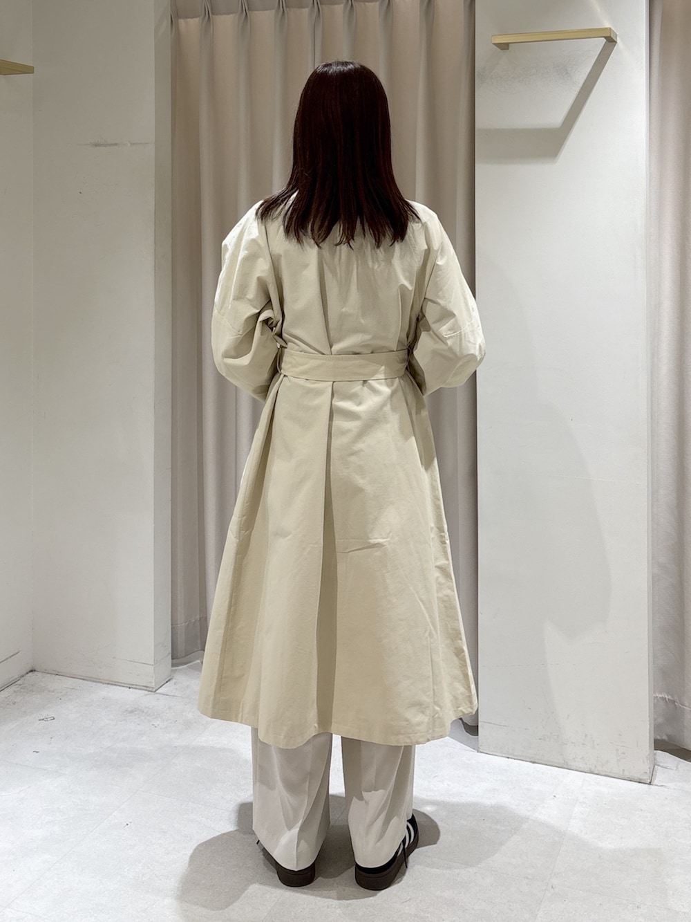 ホワイト系のトレンチコート、ベージュ系のニット/セーター、ブラック系のスニーカーを着用したレディースの冬コーディネートの3枚目の写真